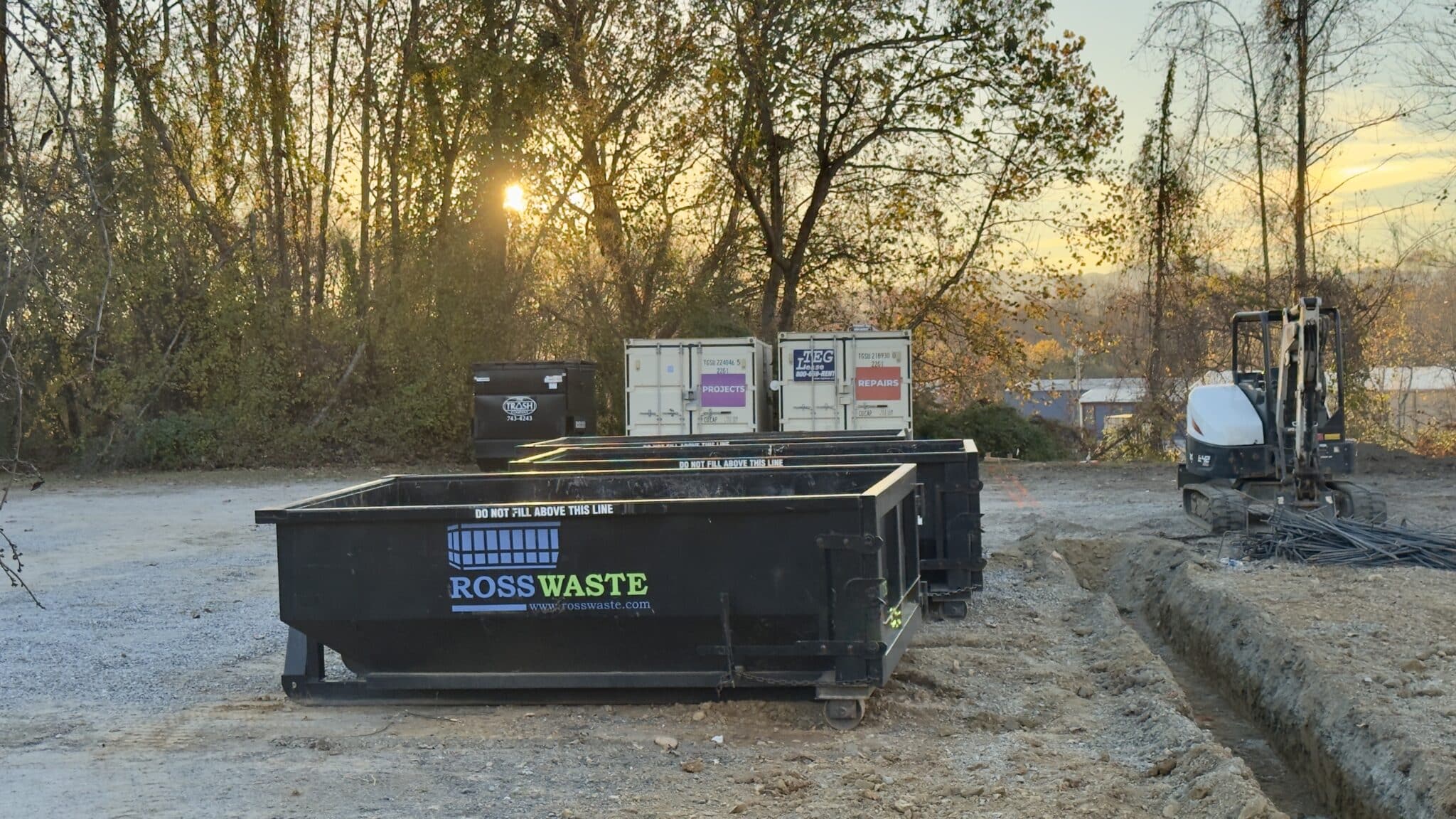 Multiple ross waste dumpster rentals at a jobsite while the sunsets